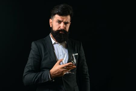 Sommelier tastes expensive alcohol drink. Handsome bearded businessman is drinking expensive cognac....