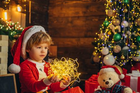 Merry and bright christmas. Childhood activity and game. Christmas attributes. Family holiday. Childhood memories. Santa boy celebrate christmas at home. Boy child play christmas decorationsの写真素材