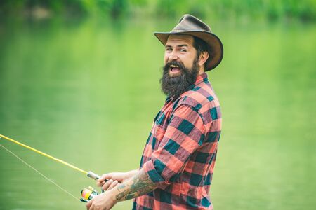 Excited fisher man fishing with spinning reel. Trout on a hook. Difference between fly fishing and regular fishing.の写真素材