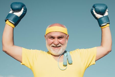 Best cardio workout. Happy Older man boxing - close up portrait. Active leisure. Senior man in gloves beats punching bag. Senior cool man fighting. I love boxing.の写真素材
