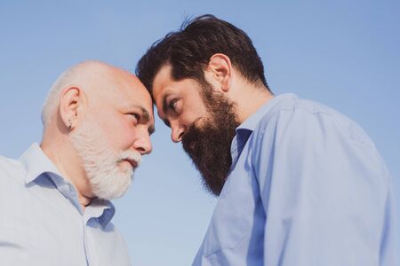 Man generations ages: grandfather and father together. Happy grandfather and father over blue sky and clouds background.の写真素材