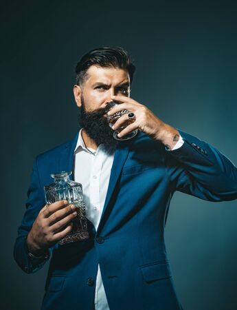 Fashion style concept. Man Bartender with beard holds glass brandy. Sommelier tastes expensive alcohol drink. Alcoholic beverage.の写真素材
