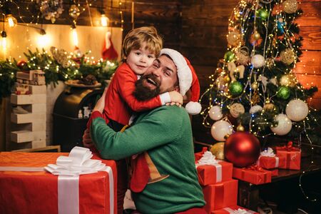 Cheerful cute child opening a Christmas present. Gift emotions. Happy son and father with Christmas gift box. New year concept The morning before Christmas.の写真素材