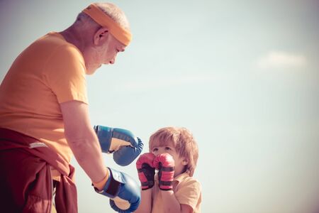 Grandpa and little child boy in boxing stance doing exercises with boxing gloves. Active leisure. Best cardio workout.の写真素材