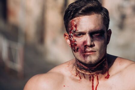 Skull make up portrait of young man. Naked man holding creepy carved halloween pumpkin. Close-up...