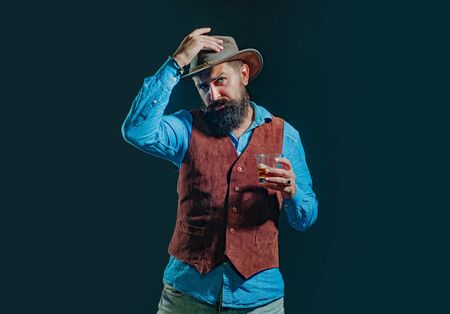 Man with beard holds glass of brandy. Sipping whiskey. Stylish rich man holding a glass of old whisky. Degustation of elite alcohol. Luxury alcohol drink.の写真素材