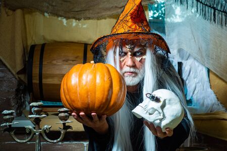 Devil man with skull with bloody face. Devil vampire man. Happy Halloween - handsome Demon isolated on dark background. Scary Halloween man in hat - studio shot close-up.の写真素材