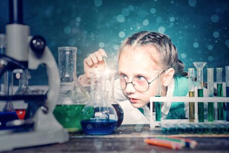 Back to school and home schooling. Happy little scientist making experiment with test tube. Portrair...