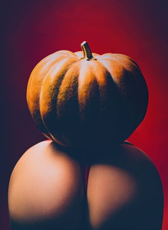 Pumpkins on ass. Female sensual ass posing with red panties and pumpkin. Halloween festival decorations. Sex costume for celebrates Halloween. Pumpkin on ass. Halloween sexy concept.の写真素材