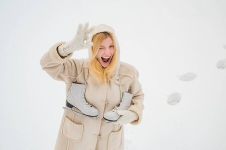 Comic face with funny grimace. Winter young woman portrait. Outdoor photo of young beautiful happy smiling girl walking on white snow Background.の写真素材