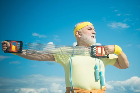Healthcare cheerful lifestyle. Freedom retirement concept. Elderly man practicing sports on blue sky...
