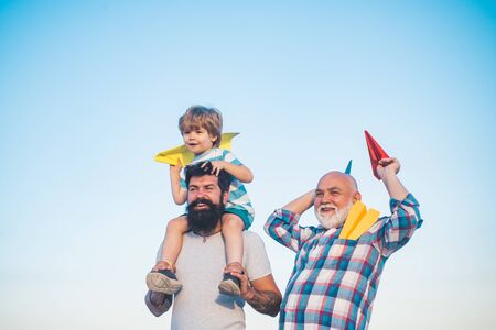 Happy man family have fun together. Childhood concept. Leisure activity. Son father and grandfather playing on blue summer sky. Fathers day concept.の写真素材