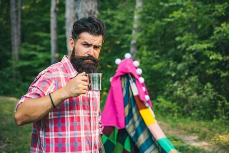 Love makes a cottage a castle. Homemade tent - hut. Camping. Homemade Tent Camping for free man. Handsome bearded man inside camping tent. Eco Resort Activities.の写真素材