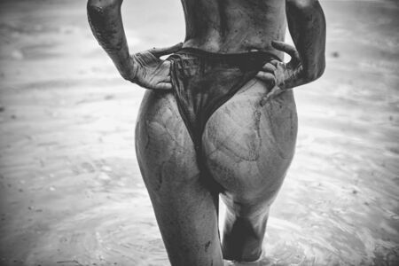 Beautiful butt in mud bath. Woman in the mud bath. Spa procedure and body care. Enjoying mud bath alternative therapy. Relax and rest concept. Nature care on spa procedure.の写真素材