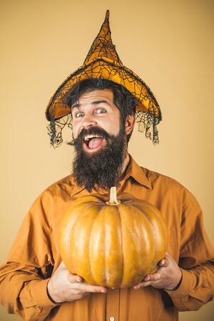 Devil man. Halloween man with pumpkin - Holidays celebration concept. Scary hipster man with beard in Halloween hat. Trick or treat. Bearded Halloween man in witch hat - studio shot close up.の写真素材