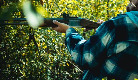 Hunter with shotgun gun on hunt. Bearded hunter man holding gun and walking in forest. Hunter with shotgun gun on hunt.の写真素材