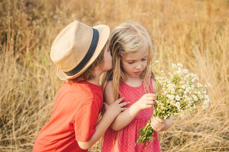 Happy Kid on summer field. Happy children girl and boy hug on meadow in summer in nature. Human emotions - kids first love. Little angels in love. Valentines day.の写真素材