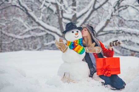 Making snowman and winter fun for girl. Winter concept. Young woman winter portrait. Christmas preparation - funny girl make snowman.の写真素材