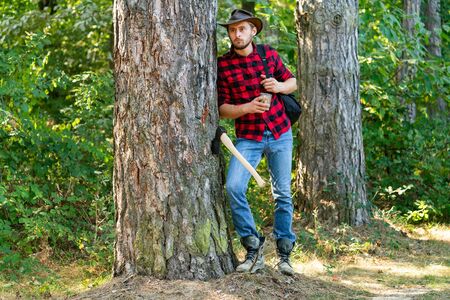 Firewood as a renewable energy source. Lumberjack with axe on forest background. Deforestation is a...