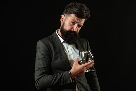 Handsome bearded businessman is drinking expensive whisky. Sommelier man. Man with beard holds glass...