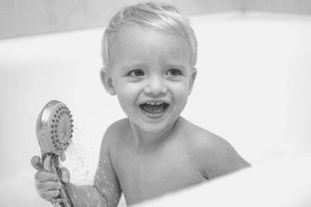 Child bubble bath. Pretty smiling little boy taking a bath with soap suds. Cute little boy washing....