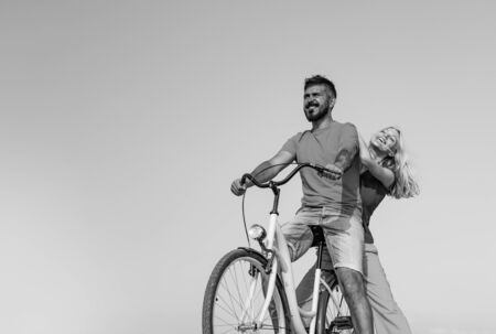 Young riders enjoying themselves on trip. Stylish and loving couple enjoying. Couple in love riding a bike. Attractive couple on a bike ride on a sunny day. Couple with vintage bike.の写真素材