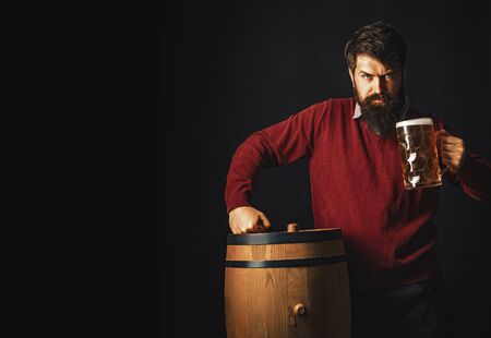 Emotional funny bearded drunk hipster holds craft bottled beer. Beer in the US. Lager and dark beer with keg or barrel of beer.の写真素材