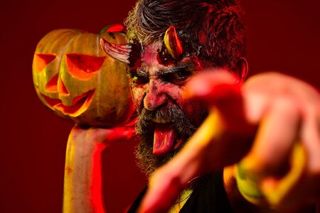 Devil man with bloody eyes hold pumpkins. Happy Halloween. Devil vampire man. Halloween Scene with...