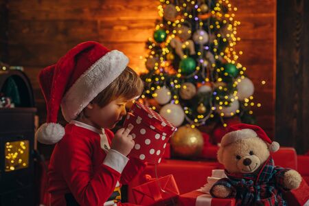 Christmas interior. New Year surprise present. Christmas attributes. Happy new year. Happy christmas. Little genius. Little boy in Santa hat and costume having fun.の写真素材