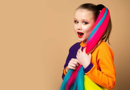 Colorful little girl makeup and rainbow hair. Fashion photo of gorgeous European little model with...