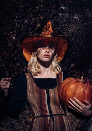 Halloween party. Halloween Witch with a carved Pumpkin and knife. Halloween Witch in magic hat with Pumpkin and knife.の写真素材