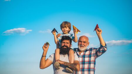 Young boy with father and grandfather enjoying together in park on blue sky background. Fathers day - grandfather, father and son are hugging and having fun together.の写真素材