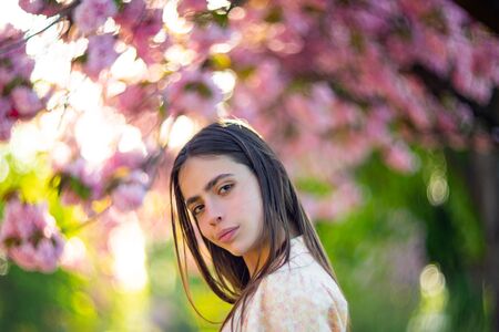 Spring girl face. Close up portrait of tender woman at sakura flowers background. Hanami celebration...