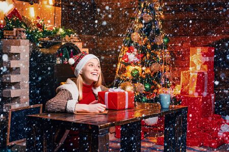 Filled with happiness cheer and love. Girl enjoy cozy warm atmosphere christmas eve. Christmas joy. Woman wooden interior christmas decorations garland lights. Christmas tree. Pleasant momentsの写真素材