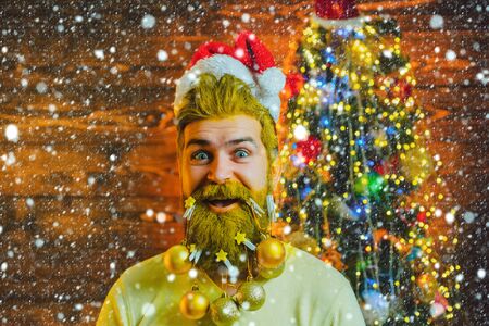 Portrait of Santa. Man in snow. Happy Christmas winter time. Home Christmas atmosphere. Santa posing on vintage wooden background.の写真素材