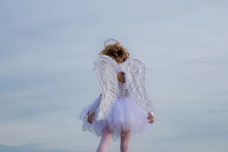 Innocent girl. Enjoying magic moment. Valentines day card. Cute teen cupid on the cloud - sky background.の写真素材