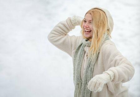 Winter woman. Cute playful young woman outdoor enjoying first snow. Happy young girl playing snowball fight. Girl in mittens hold snowball.の写真素材