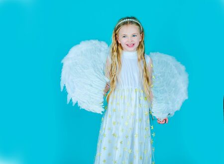 Beautiful young girl wearing angel wings. Child wearing long white dress and angel wings. Cute toddler girl in white wings as Cupid.の写真素材