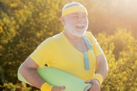 Elderly man practicing sports on blue sky background. Senior man is doing fitness training. Freedom retirement concept.の写真素材