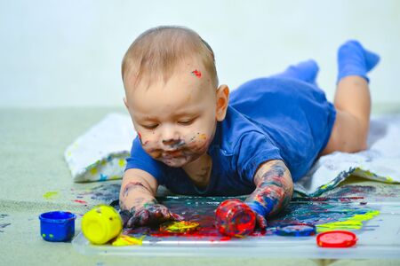 Happy baby child draws with colored paints hands. Happy child draws. Beautiful baby covered in bright paint. Painted in skin hands. Copy space. Early learning. White background.の写真素材