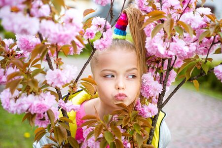 Nice schoolgirl portrait in spring garden. Expressive look. Spring smile. Smiling happy child. Fashionable multicolor photoshoot.の写真素材