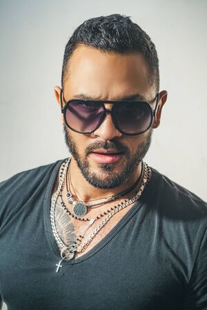Charming man with sunglasses. Man face. Portrait of a handsome masculine man. Portrait of satisfied businessman against grey wall. Sunglasses. City fashion style.の写真素材