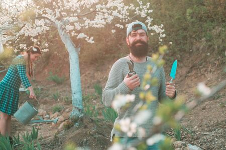 Gardener planting in spring garden. Garden man with tools. Farmer work in yard with garden tools and...