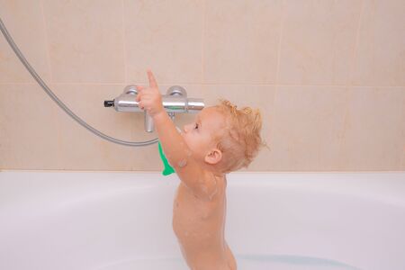 Happy baby having a bath and playing with toys. Kids bath soap. Baby have fun in the bath with soap....