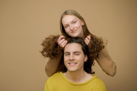 Handsome man with long wavy hair and his cute girlfriend. Beautiful girl playing with her boyfriend...