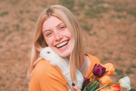Easter Bunny. Little girl having fun on Easter egg hunt. Beautiful young woman with bunny rabbit on farm.の写真素材