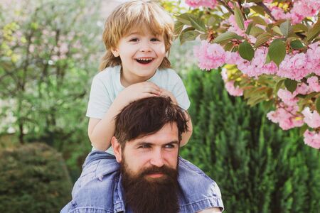 Two generations ages: father and son piggyback ride together. Happy father and son. Happy childhood concept.の写真素材