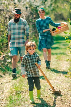 Family planting. Son helper. Family walking in agricultural field. Son help Family working on organic farm in spring. Portrait of a young happy family in yard during spring season.の写真素材