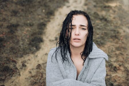 Beautiful girl got wet in the rain and froze. Upset sensual girl with wet hair looking at camera. Adorable attractive woman was caught in a thunderstorm.の写真素材