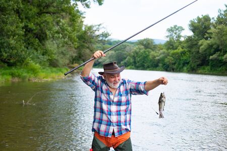 Mature man fly fishing. Fish on hook. Bearded fisher in water. Fishing skills. Fly fishing...